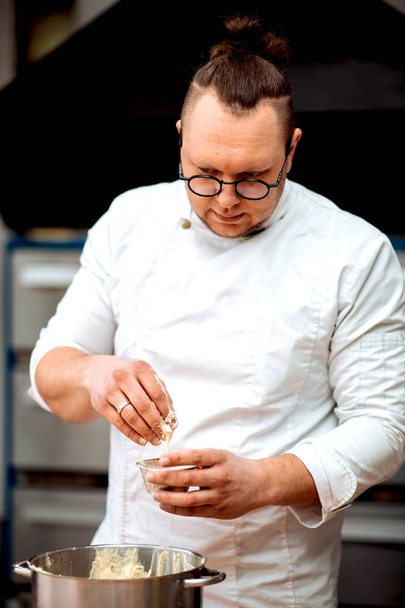 Um homem chef prepara cupcakes na cozinha
 - Foto, Imagem