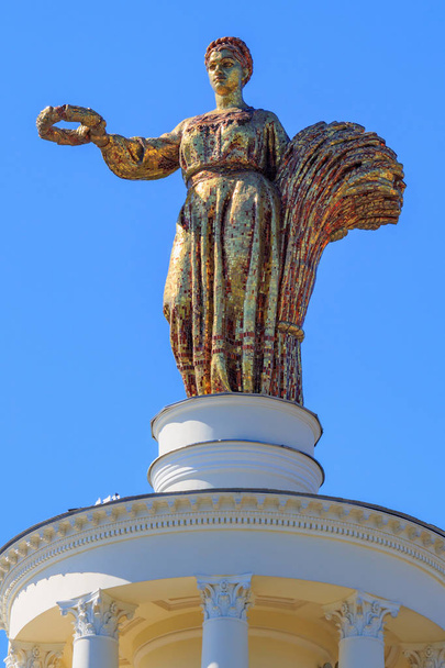 Moscow, Russia - August 01, 2018: Figure of woman of collective farmer closeup against blue sky on a roof of pavilion Republic Of Belarus on Exhibition of Achievements of National Economy (VDNH) in Moscow - Fotografie, Obrázek