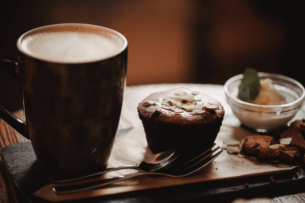 Close up food image of cup of coffee and dessert on the wooden table backgrouund in cafe. Trend warm toning. Photo with a small depth of field. - Foto, Imagen