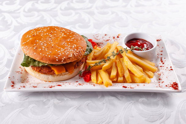 Fast food restaurant menu. Huisgemaakte hamburger met rundvlees pasteitjes, ui, tomaat, sla en kaas. Verse Hamburger close-up. Gegarneerd met gouden frietjes aardappelen - Foto, afbeelding