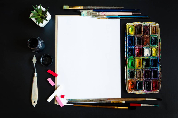 Creative artist workplace flat lay, mockup. Top view on table with blank sheet of paper, paintbrushes and dye palettes. Art, workshop, painting, drawing, craft, creativity concept. Copy space. - Photo, Image