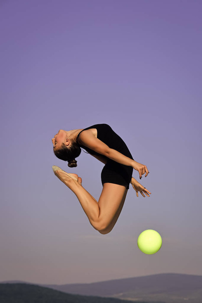 Woman gymnast with green ball on blue sky background - Foto, immagini