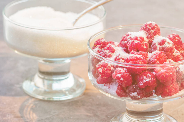 Glass of fresh raspberries sprinkled with white sugar gardening gastronomy harvest summer evening sunset light Concept home made ingredient recipe for cooking jam and cookware - Foto, imagen