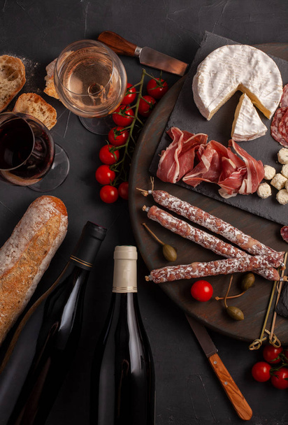 Appetizers table with differents antipasti, cheese, charcuterie, snacks and wine. Mini burgers, sausage, ham, tapas, olives, cheese and baguette over grey concrete background. Top view, flat lay - Фото, зображення
