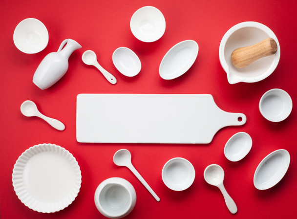 White tableware and kitchen utensils over the reg backgtound. Mockup, cooking blog and classes concept - Photo, Image