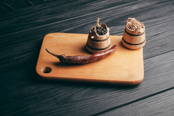 Koření: pepř, červený pepř, chili lež na hnědé dřevěné desce na černém stole. Umístěte pod textem - Fotografie, Obrázek