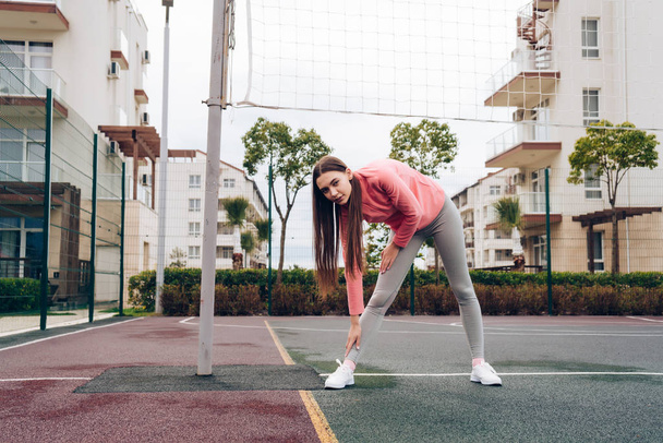 active long-haired girl in a pink jacket stretches before training, wants to lose weight - Foto, immagini