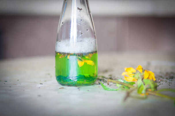 a love potion on a table with a yellow flower. magic and magic. - Фото, изображение