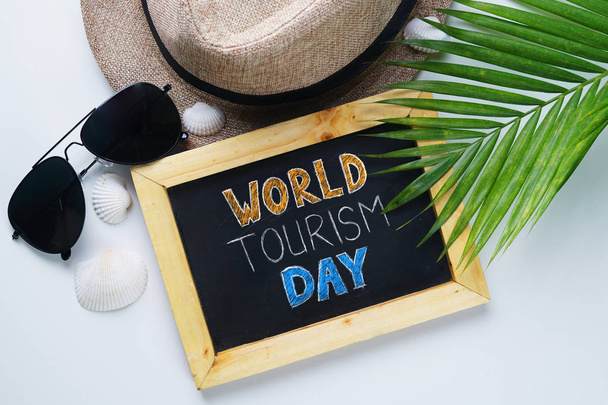 Dünya Turizm günü tipografi. Güneş gözlüğü, arka plan Fedora şapka, palmiye yaprağı, deniz kabukları. - Fotoğraf, Görsel