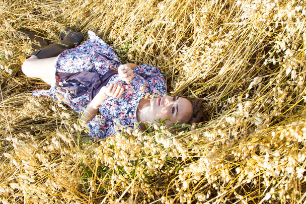 Young girl lies in a field with mature ears - Foto, afbeelding