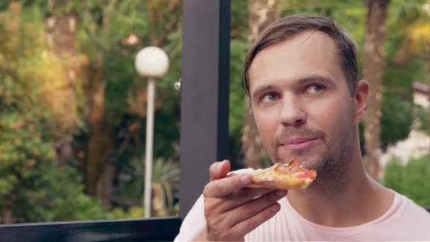 Όμορφη νεαρός άνδρας τρώει ένα κομμάτι πίτσα στο café. γκρο πλαν, 4k, αργή κίνηση - Πλάνα, βίντεο