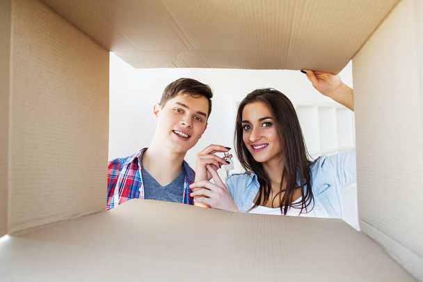 glückliches junges Paar packt Kisten aus und zieht in ein neues Zuhause. - Foto, Bild