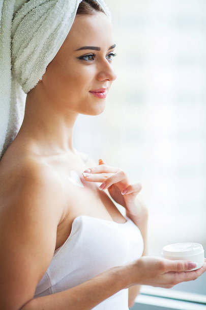 Attractive girl putting anti-aging cream on her face. - Photo, Image