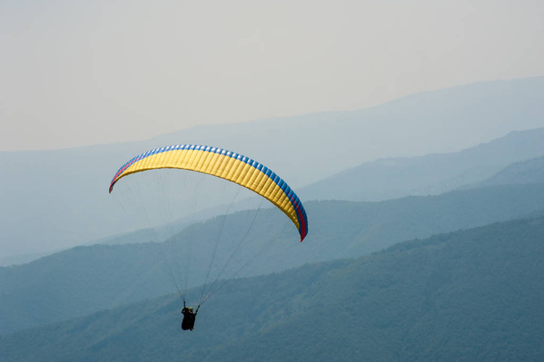 Parapente voa sobre um vale de montanha em um dia ensolarado de verão. Parapente nos Cárpatos no verão
. - Foto, Imagem