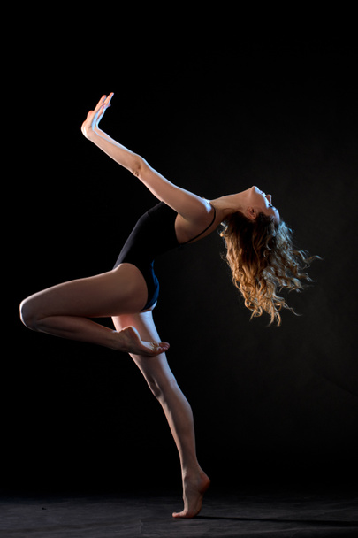 Slim bailarino em movimento no fundo do estúdio preto
 - Foto, Imagem