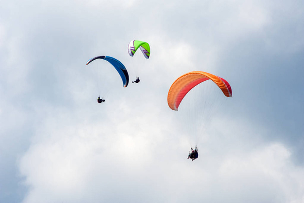 Trois parapentistes volant dans le ciel bleu sur fond de nuages. Parapente dans le ciel par une journée ensoleillée
. - Photo, image