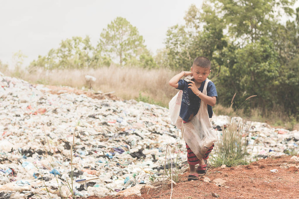 Child carrying a garbage bag to sell, the lives and lifestyles of the poor, The concept of child labor and trafficking - Photo, Image