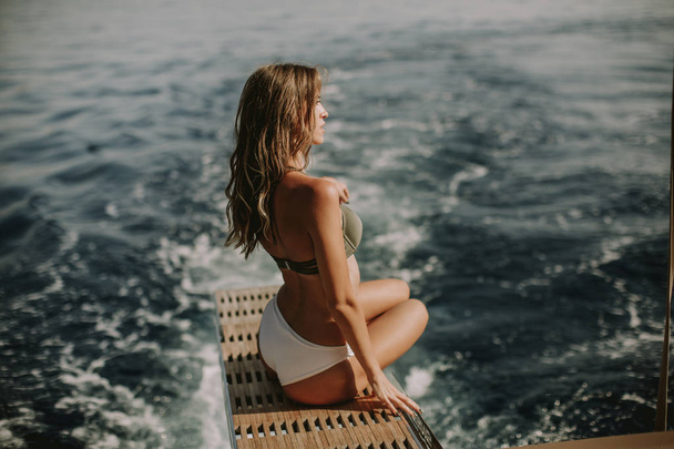 View at young attractive woman sitting on  luxury yacht floating at sea - Photo, Image