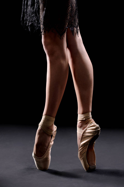 ballet dancer legs pointes on black backgrownd - Fotó, kép