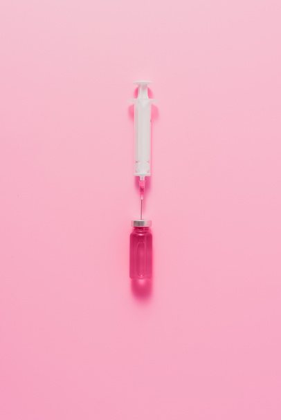 top view of syringe with ampule of pink liquid on pink surface - 写真・画像