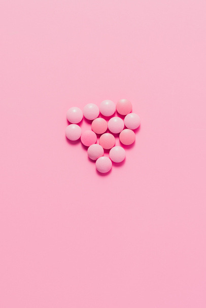 top view of heap of pink pills on pink surface - Foto, imagen