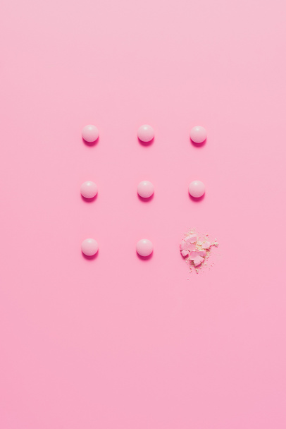 вид зверху розставлені рожеві таблетки на рожевій поверхні
 - Фото, зображення