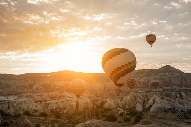 Ballonnen tegen de achtergrond van de rotsen bij dageraad. Grote veelkleurige ballen in het zonlicht van de dageraad. Turkije. Cappadocië. Goreme Nationaal Park. - Foto, afbeelding