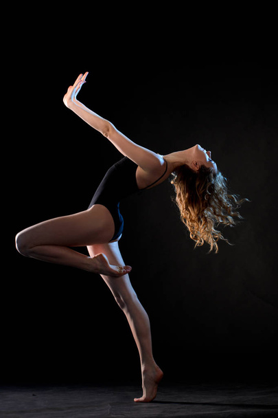 Slim ballet dancer in motion on black studio background - Photo, Image