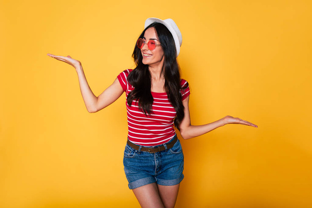 young brunette woman in white hat and glasses posing on yellow background  - Photo, image