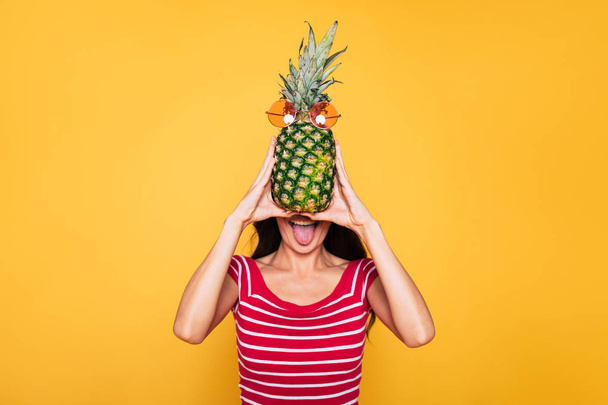 young brunette woman posing with pineapple on yellow background  - Photo, Image