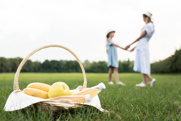 wicker basket with fresh fruits and mom with daughter on background, selective focus - Photo, Image