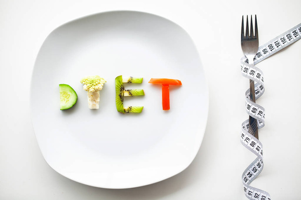 Diet or weight control concept. Centimeter tape and fork on a white background with a place for inserting text. concept of health, weight loss, diet, proper nutrition. - Photo, Image