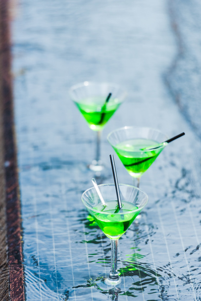 close up view of glasses with green cocktails with straws at poolside - Foto, Imagem
