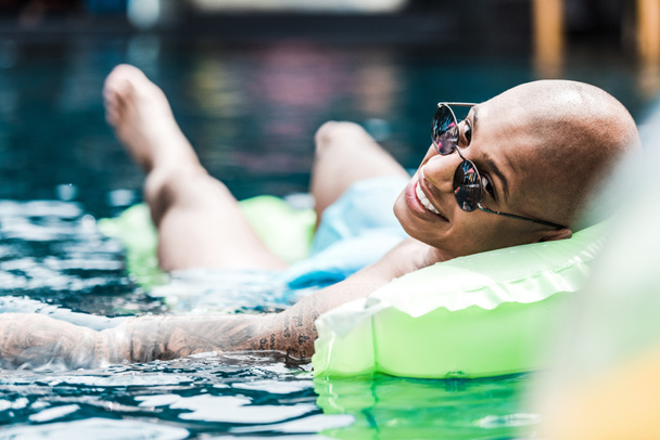 homme souriant reposant sur un matelas gonflable regardant la caméra dans la piscine
  - Photo, image