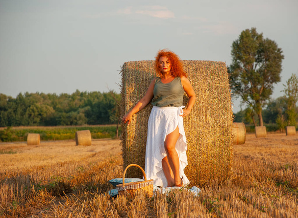 Femme rousse posant sur le terrain près d'une meule de foin
 - Photo, image