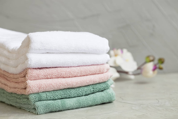 Pilha de toalhas de banho de algodão limpo no fundo de concreto, lavanderia ou conceito de banheiro
 - Foto, Imagem