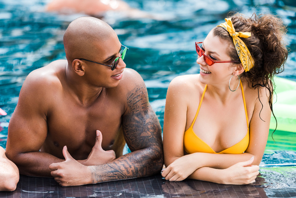 молодые люди в солнцезащитных очках смотрят друг на друга в бассейне
  - Фото, изображение