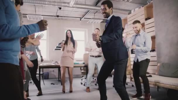 Wesoły wieloetnicznym przedsiębiorcy tańczyć razem zdrowe biuro teambuilding imprezie, świętować sukces zwolnionym tempie. - Materiał filmowy, wideo