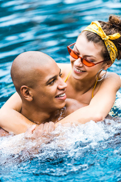 hymyilevä nainen syleilee poikaystävä uima-altaassa
  - Valokuva, kuva
