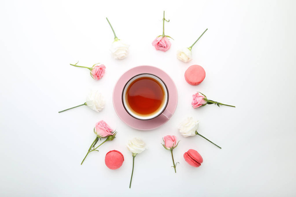 Rose flowers with cup of tea and macaroons on white background - Фото, зображення