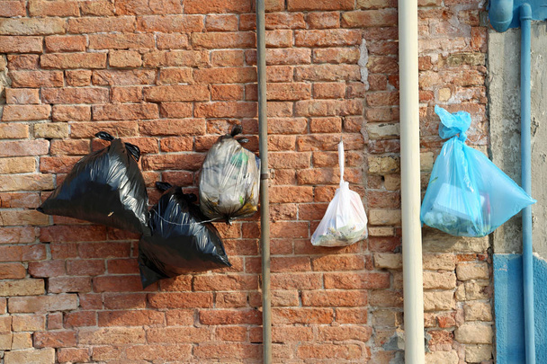 σακούλες σκουπιδιών που κρέμονται στον τοίχο των σπιτιών για την πρόληψη αρουραίους από το φαγητό τους ή ότι τα αδέσποτα ζώα σπάσουν τα εμπορευματοκιβώτια - Φωτογραφία, εικόνα