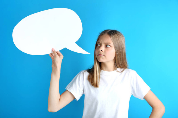 Young angry girl holding speech bubble on blue background - Фото, изображение