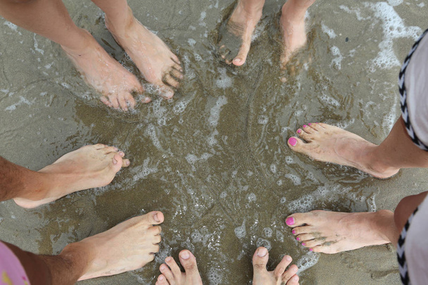 βρεγμένα πόδια από τα κύματα της θάλασσας από μια οικογένεια 5 ατόμων το καλοκαίρι - Φωτογραφία, εικόνα