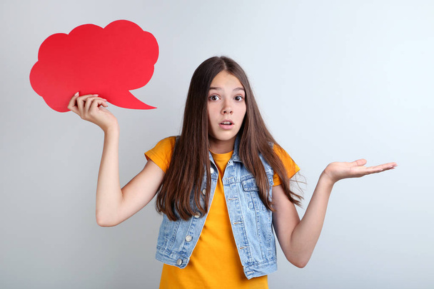 surprised girl holding red speech bubble on grey background - Фото, изображение