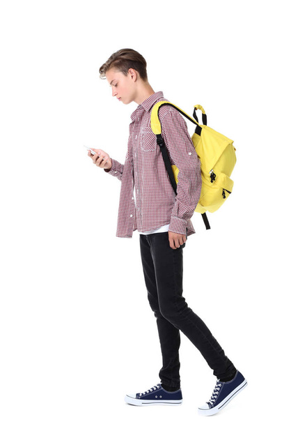 Young boy with yellow backpack using smartphone isolated on white background - Fotoğraf, Görsel