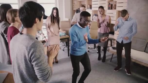 Vrolijke African American manager dansen in een cirkel met collega's op leuke casual office viering partij Slowmotion. - Video