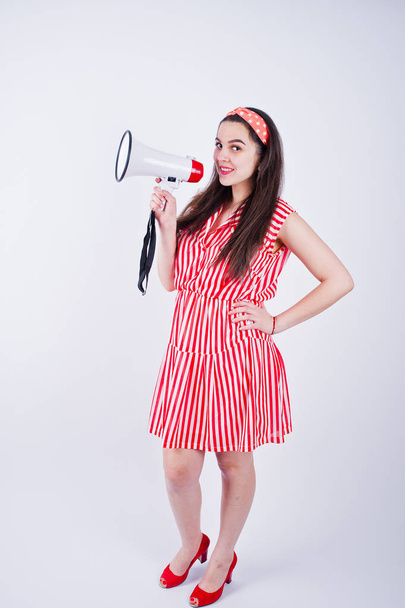 Portrait of a young beautiful woman in red dress talking into megaphone. - 写真・画像