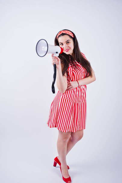 Portrait of a young beautiful woman in red dress talking into megaphone. - Фото, изображение