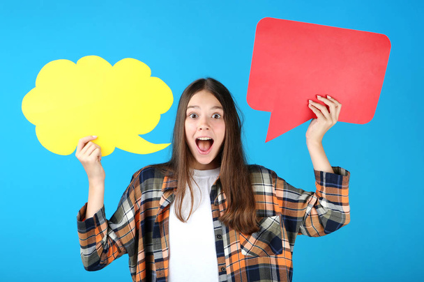 Young girl holding cardboard speech bubbles on blue background - Foto, Bild