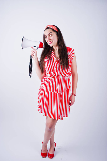 Portrait of a young beautiful woman in red dress talking into megaphone. - Zdjęcie, obraz
